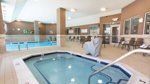 Un área de piscina hotelera con un jacuzzi, sillas de descanso y suelo de baldosas.