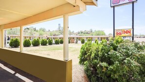 A motel with a covered parking area, a sign for Route 66 Inn, and a row of small trees. - Route 66 Inn (Santa Rosa)