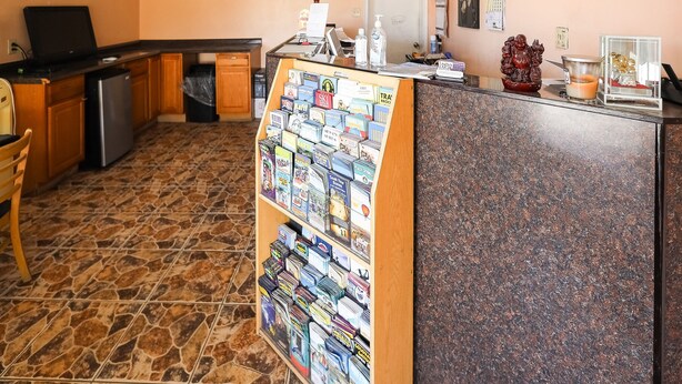 A reception area with a counter, a display of postcards, a refrigerator, and a trash bin. - Route 66 Inn (Santa Rosa)