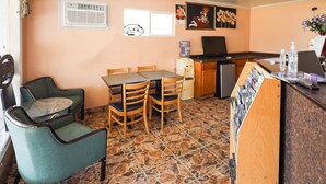 A small, cozy room with a dining table, two chairs, a refrigerator, a water dispenser, and a small TV. - Route 66 Inn (Santa Rosa)
