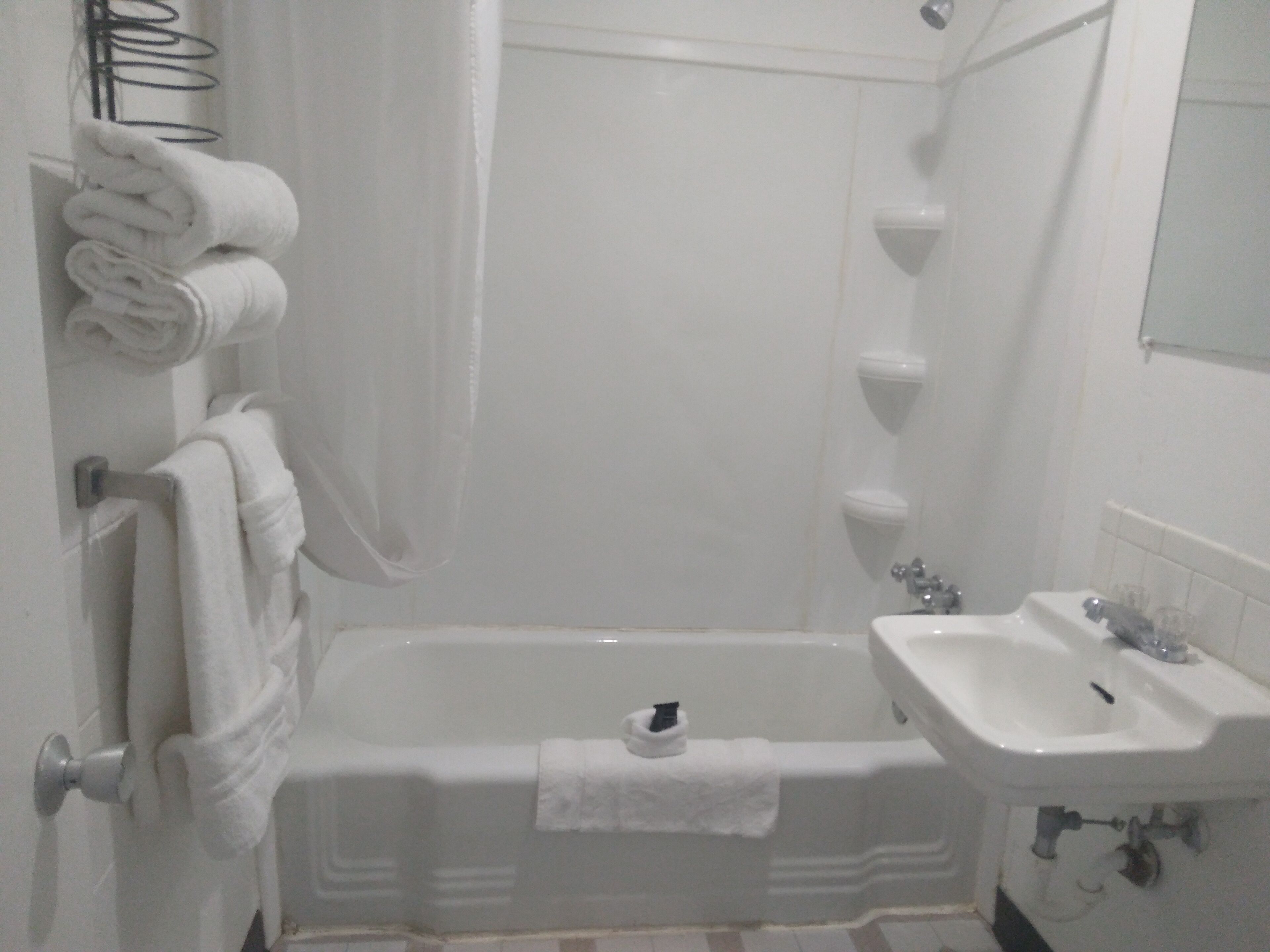 Une salle de bain avec une baignoire, un lavabo et un porte-serviettes sur lequel sont pliées des serviettes.