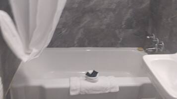 A bathroom with a bathtub, a sink, and a marble wall.