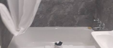 Un baño con bañera, lavamanos y pared de mármol.