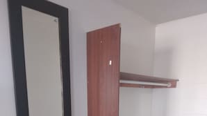 A room with a dark wooden bench, a mirror, and a white brick wall.