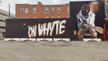 A mural of a musician on a building wall with the text "ON WHYTE" and a parking lot in front.