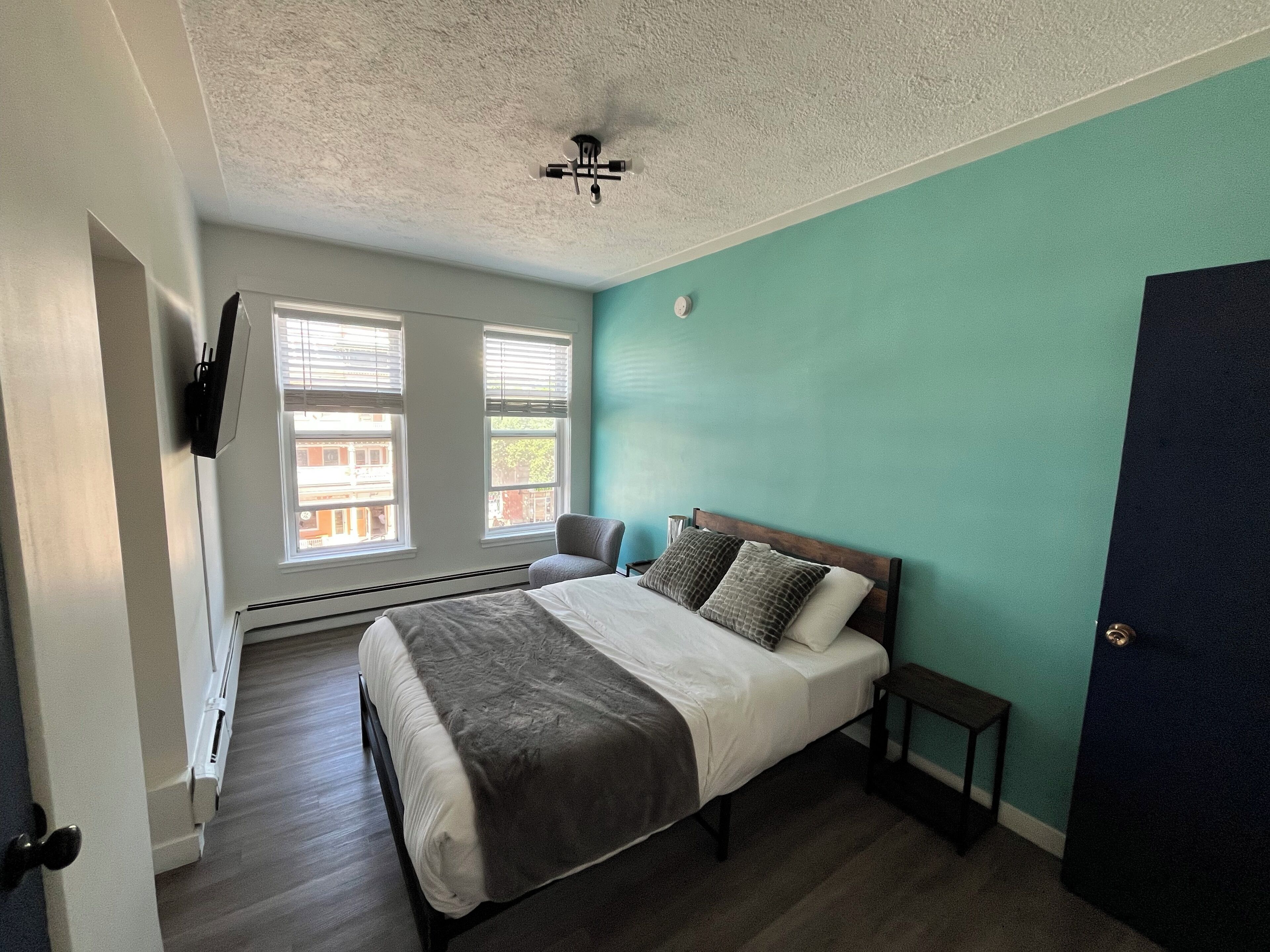 A bedroom with a bed, a chair, a heater, and a door.