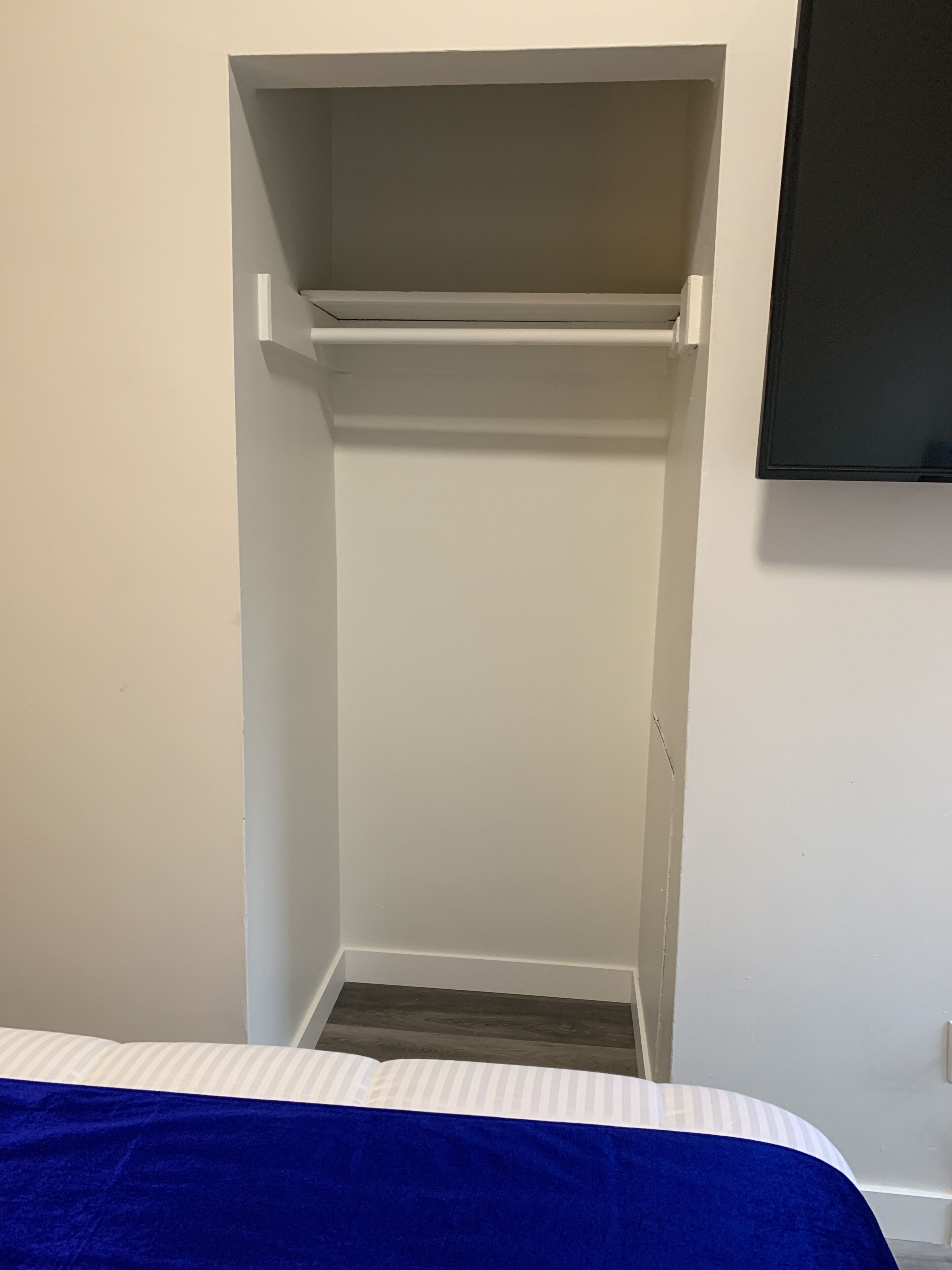 Un dormitorio con cama, armario y televisor montado en la pared.
