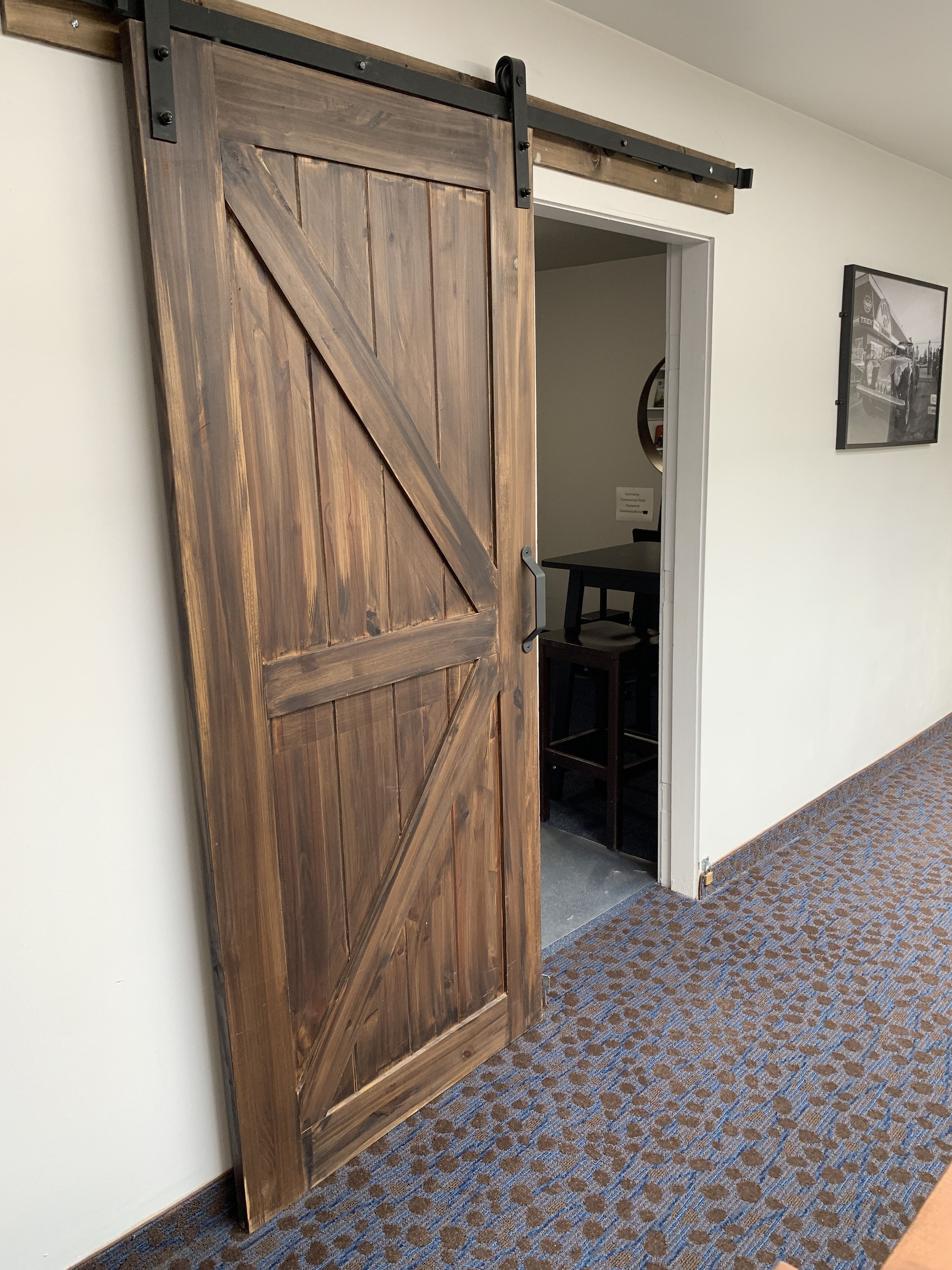 Una puerta corredera estilo granero en un pasillo con alfombra estampada.
