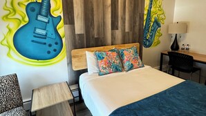 Een hotelkamer met een bed, een stoel, een bureau en een muurschildering van een gitaar en een saxofoon.