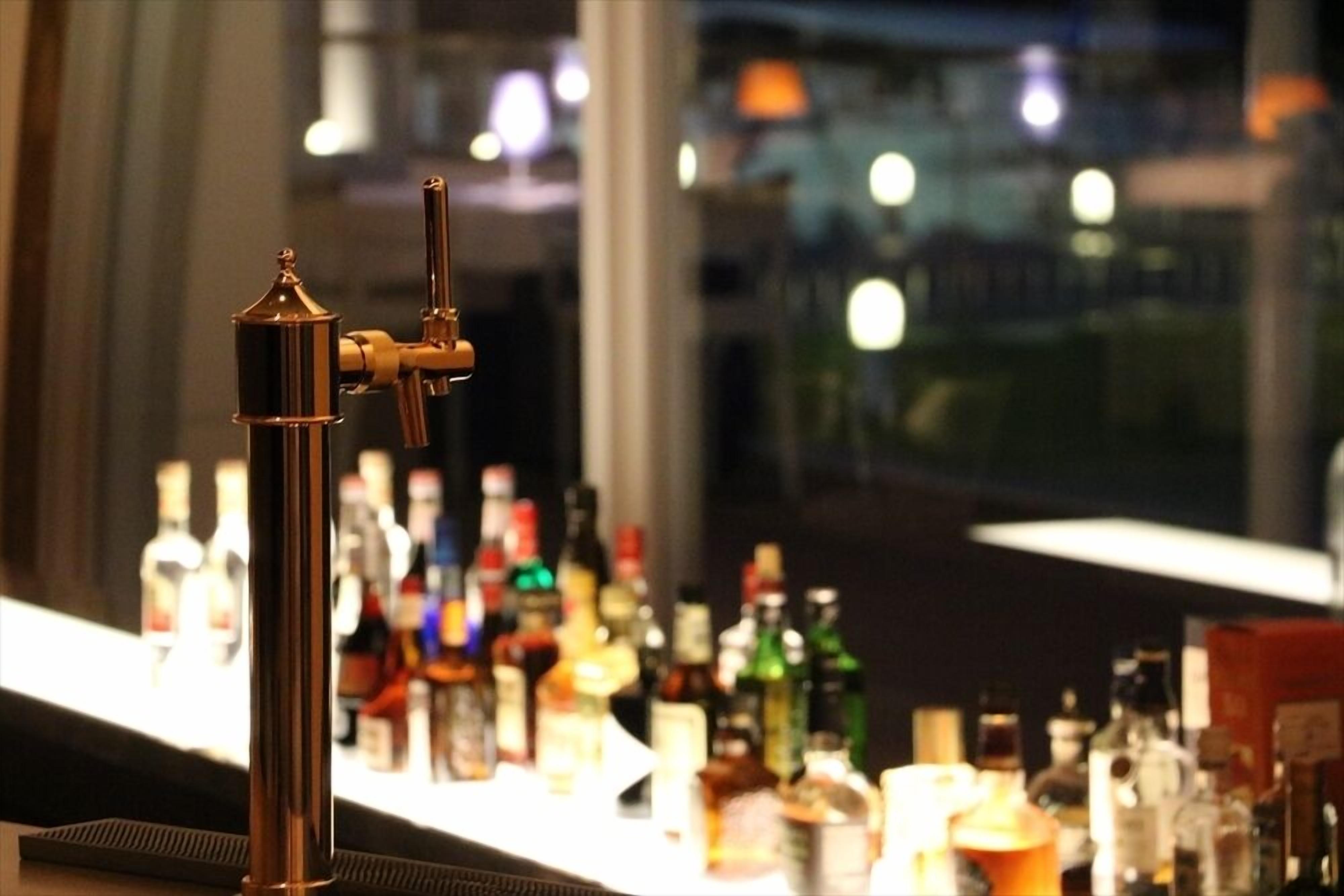 Uma área de bar com uma torneira e diversas garrafas ao fundo.