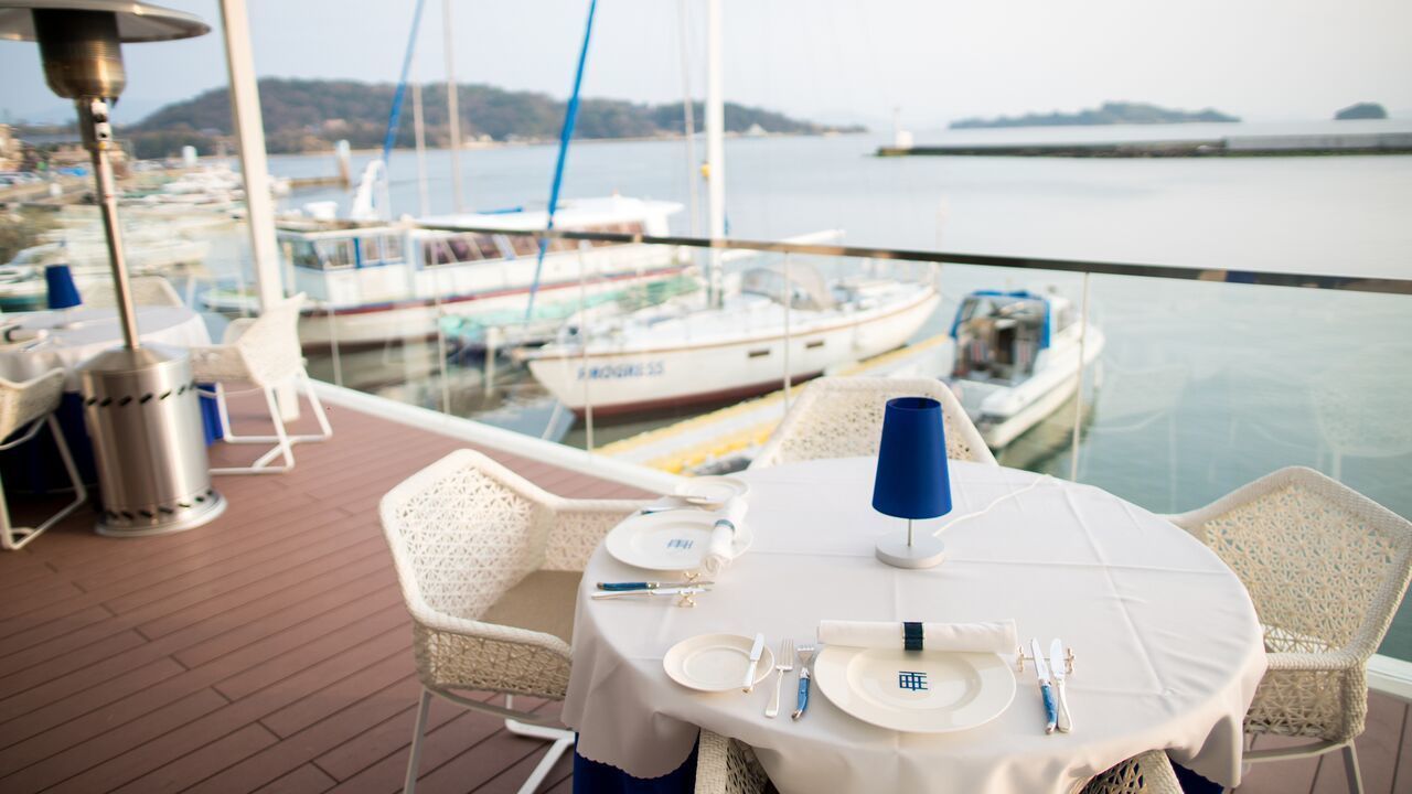 A table set for dining with a view of boats and water.