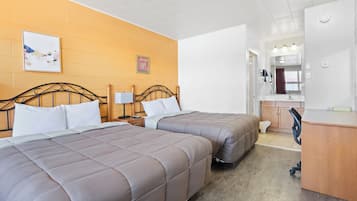 Et hotelværelse med to senge, et skrivebord, et spejl og et badeværelse, der kan ses igennem en åben dør.