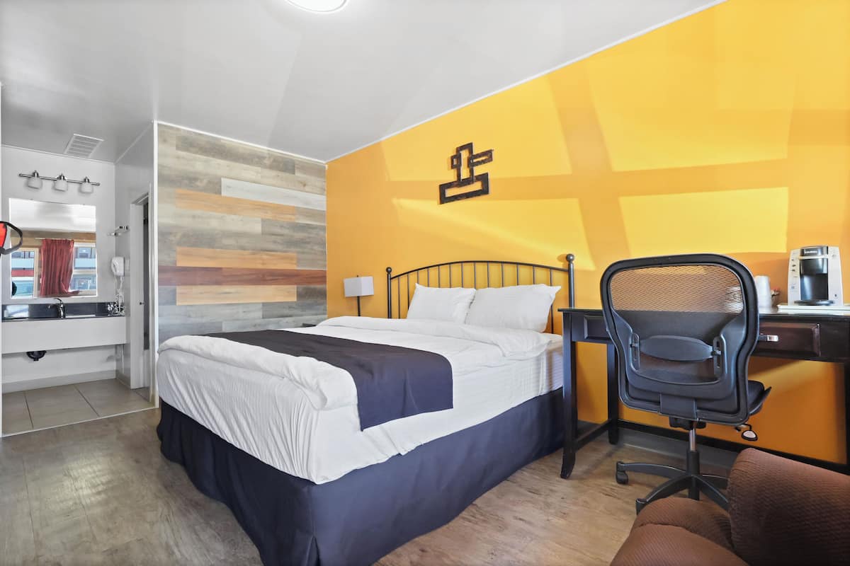 Une chambre d’hôtel avec un lit, un bureau et une chaise.