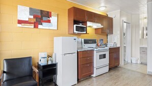 A compact kitchen with a refrigerator, microwave, stove, and wooden cabinets. - Dauphin Inn Express (Dauphin)