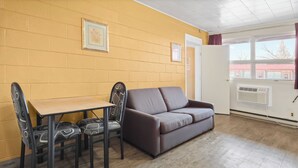 A room with a brown sofa, a wooden table, and two patterned chairs. - Dauphin Inn Express (Dauphin)