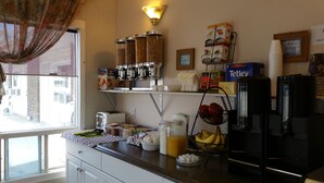 A kitchen with a window, a refrigerator, a toaster, a coffee maker, and various food items on the counter. - Athabasca Lodge Motel (Athabasca)