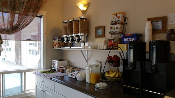 Une cuisine avec une fenêtre, un réfrigérateur, un grille-pain, une machine à café et divers aliments sur le plan de travail.