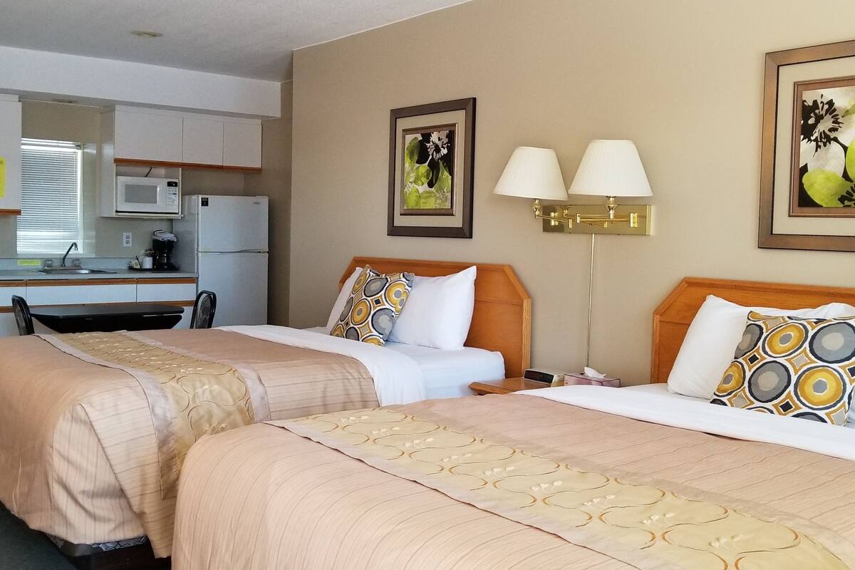 A hotel room with two beds, a kitchenette, and a dining area.