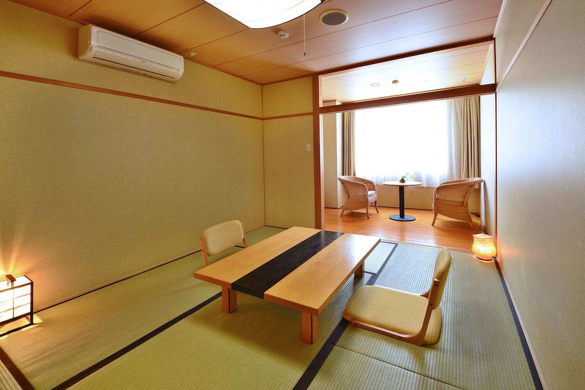 A traditional Japanese-style room with tatami flooring, a low table, and two chairs.