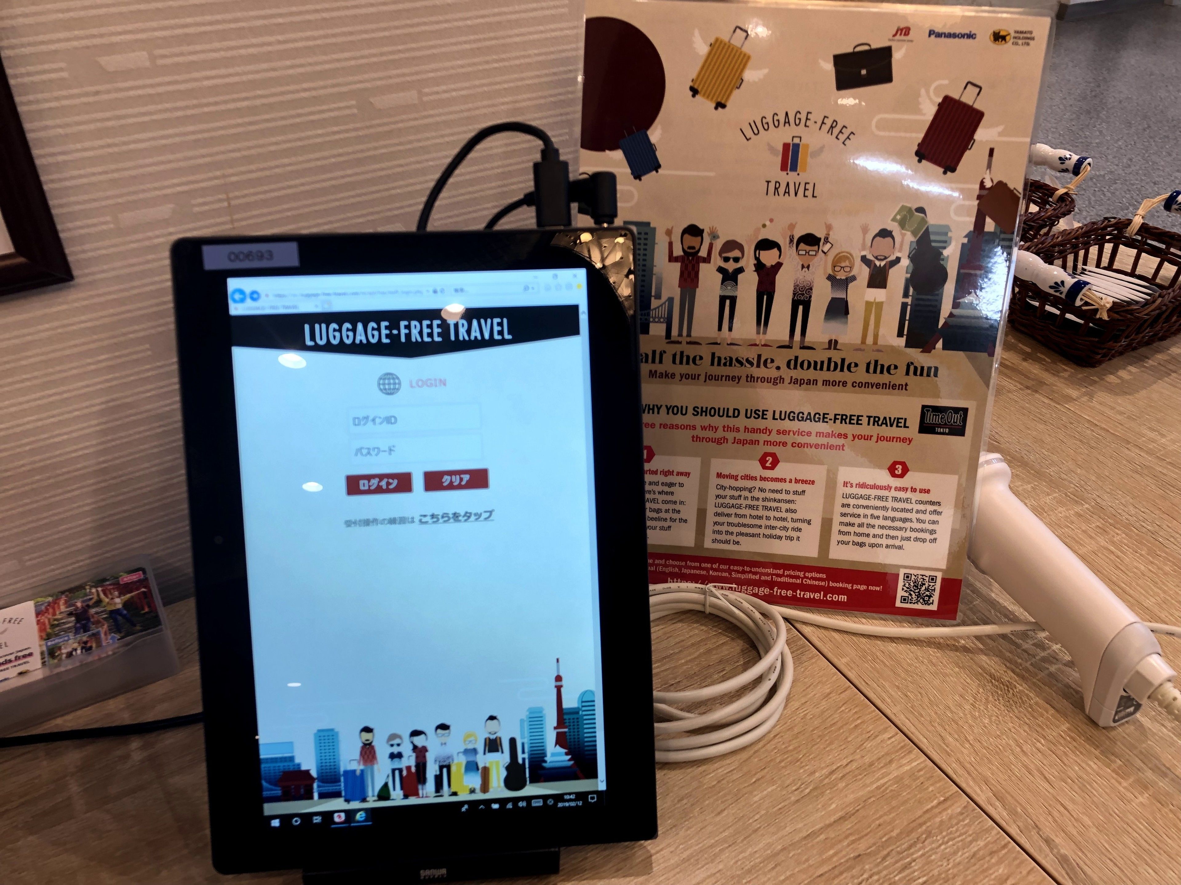 A computer monitor displaying a 'Luggage-Free Travel' website with a login page.
