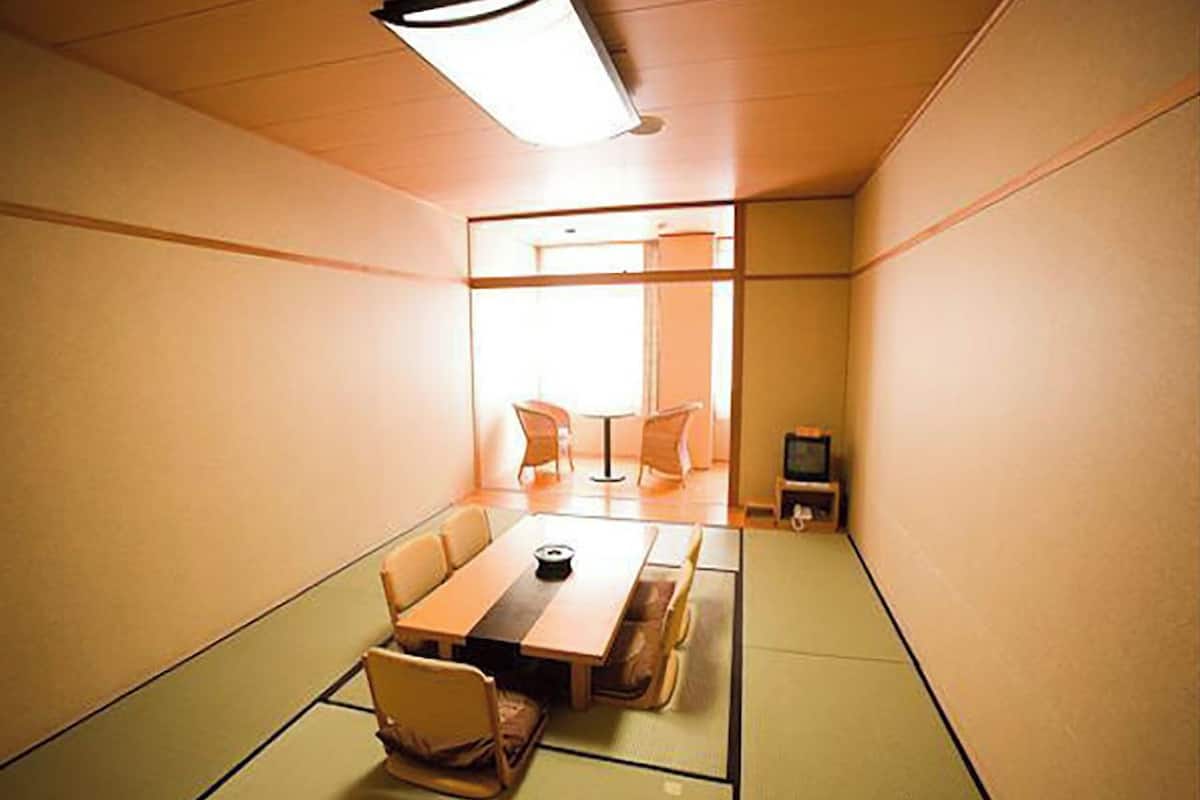 A traditional Japanese-style room with tatami flooring, a low table, and a television.