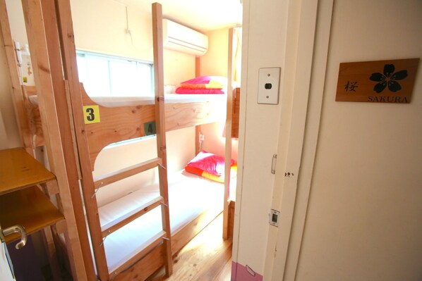 A bunk bed room with a wooden ladder, a number '3' sign, and a door with a 'SAKURA' sign. - Yadoya Guesthouse Green - Hostel (Tokyo)