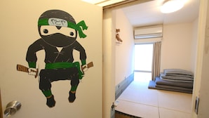 A room with a bunk bed, a wall with a ninja-themed decoration, and a window with curtains. - Yadoya Guesthouse Green - Hostel (Tokyo)