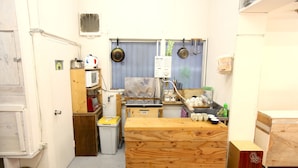 A compact kitchen with a wooden countertop, a microwave, and hanging pots. - Yadoya Guesthouse Green - Hostel (Tokyo)