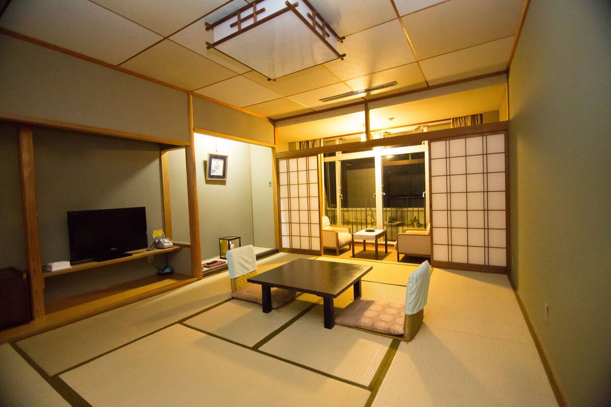 Una habitació japonesa tradicional amb terra de tatami, una taula baixa, una televisió i portes corredisses.
