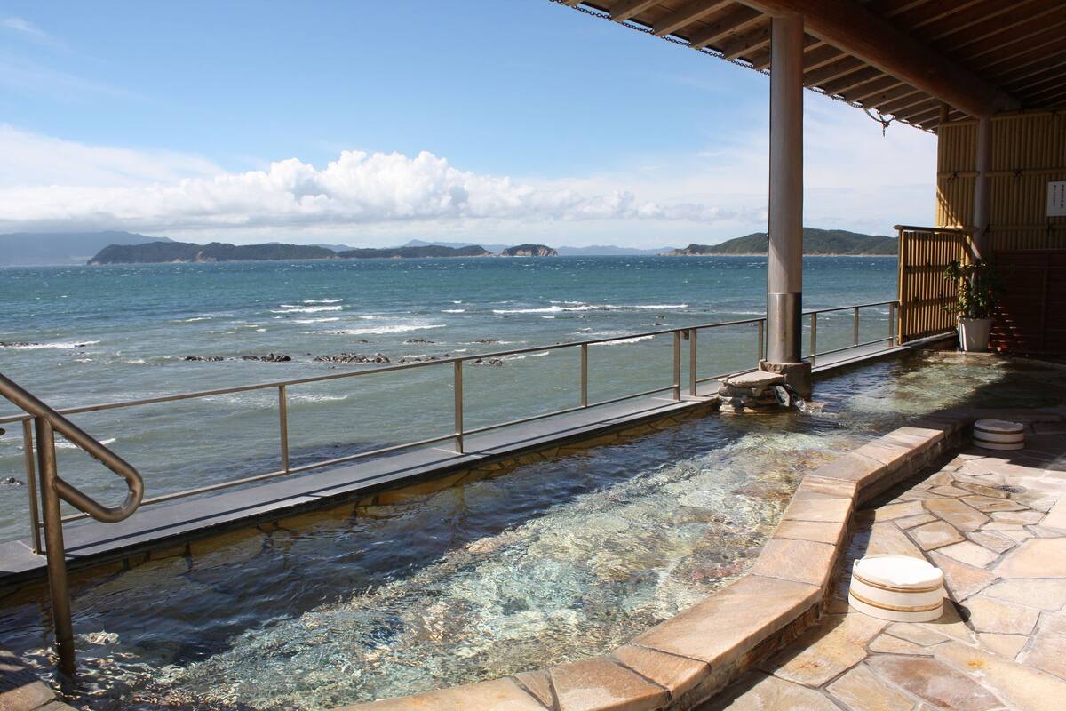 Una piscina de pedra amb barana metàl·lica que domina una massa d'aigua i illes llunyanes.