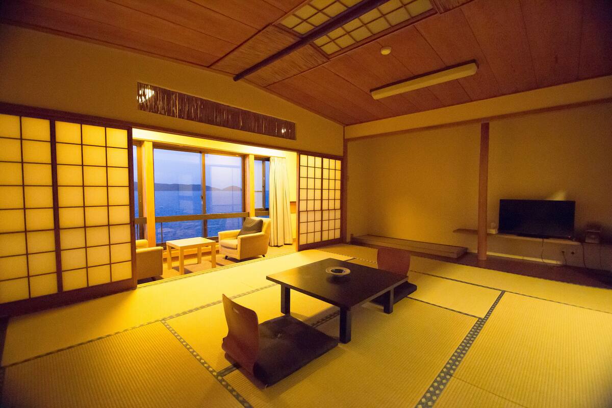 Una habitació japonesa tradicional amb fons de tatami, una taula baixa i un sofà.