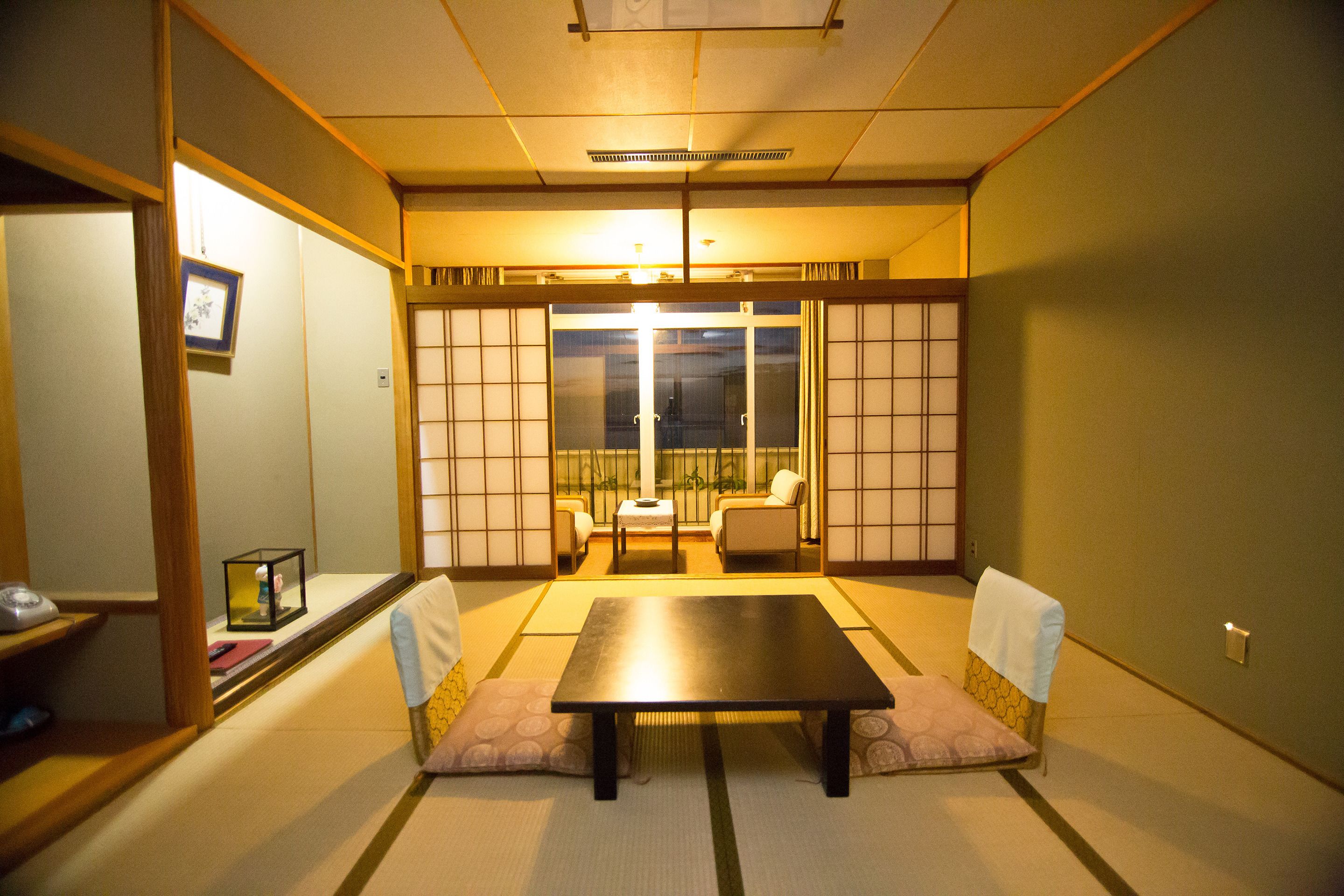 Ett traditionellt japanskt rum med tatamimattor på golvet, ett lågt bord och shojiskärmar.