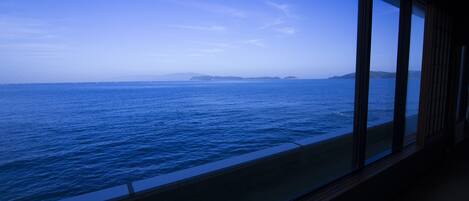 Vista desde una ventana sobre un mar tranquilo con formas de tierra en la distancia.