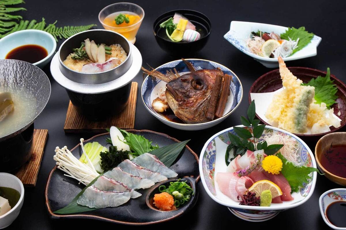 Varietat de plats japonesos, com ara sushi, sashimi i tempura, servits en ceràmica i lac decoratius tradicionals.