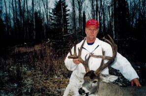 A person holding a large deer with antlers in a forested area. - Hawkrock Wilderness Adventures (Porcupine Plain)