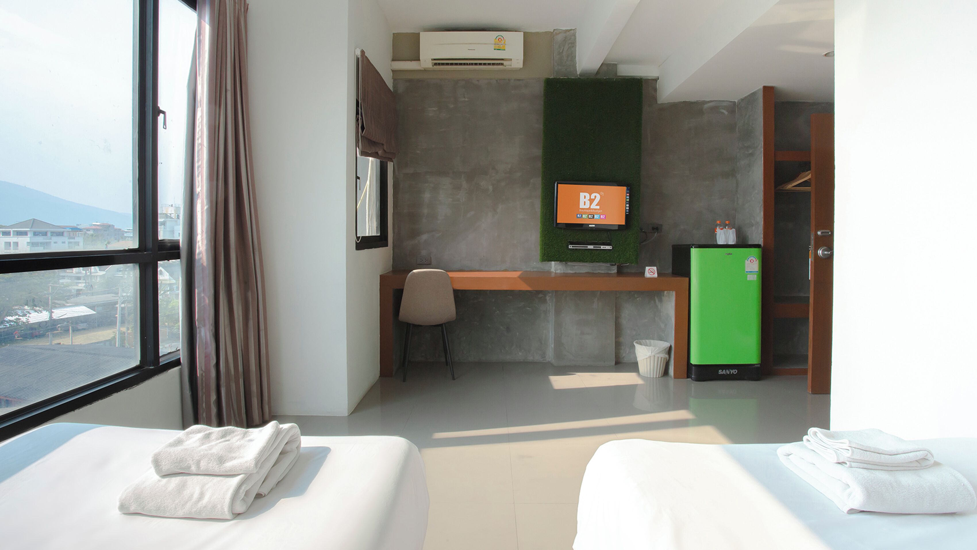 Une chambre d’hôtel équipée d’un lit, d’un bureau, d’une chaise, d’une télévision et offrant une vue sur l’extérieur.