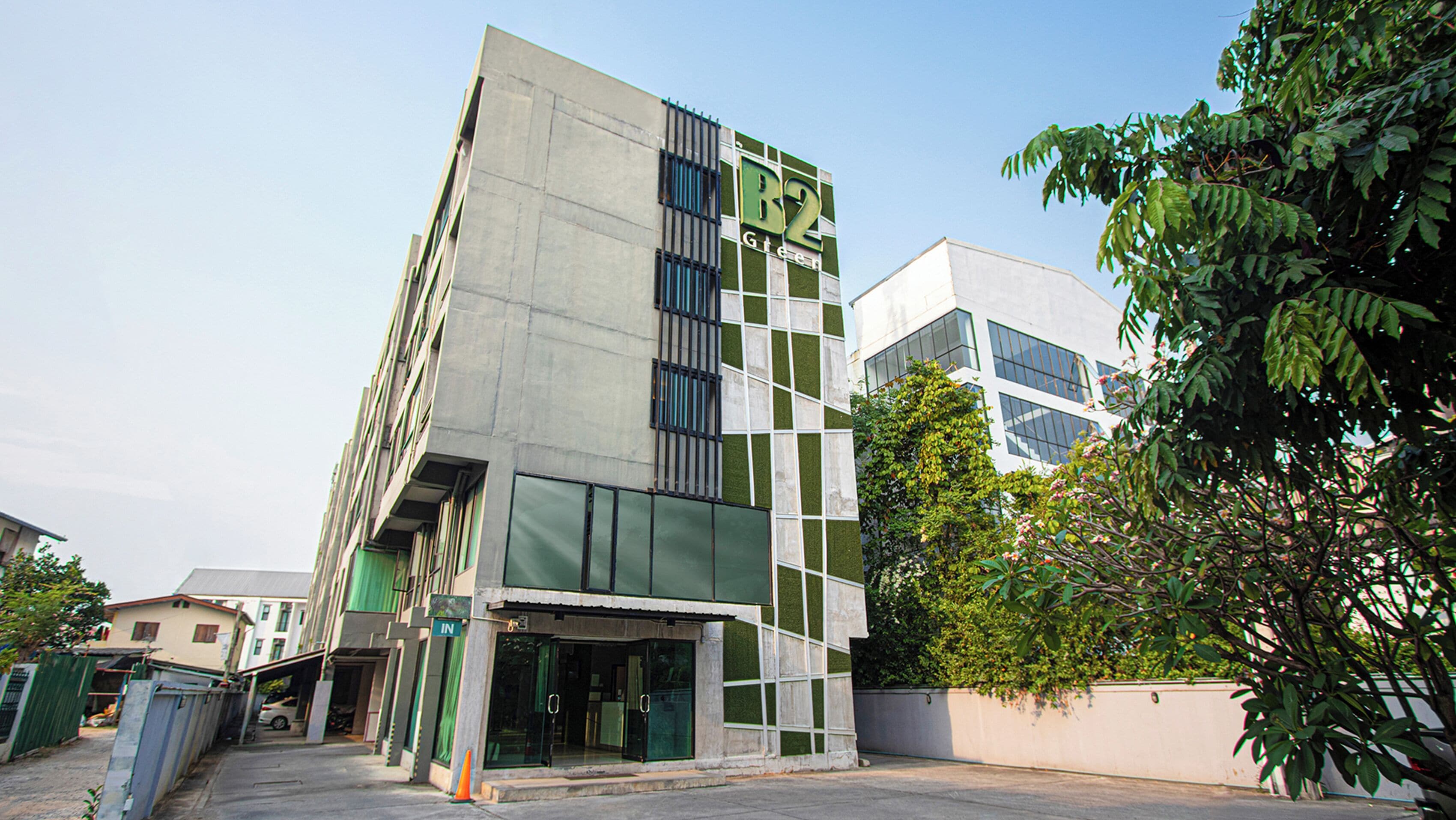 Un edificio moderno con facciata verde e bianca, ampie finestre e un ingresso ben visibile.
