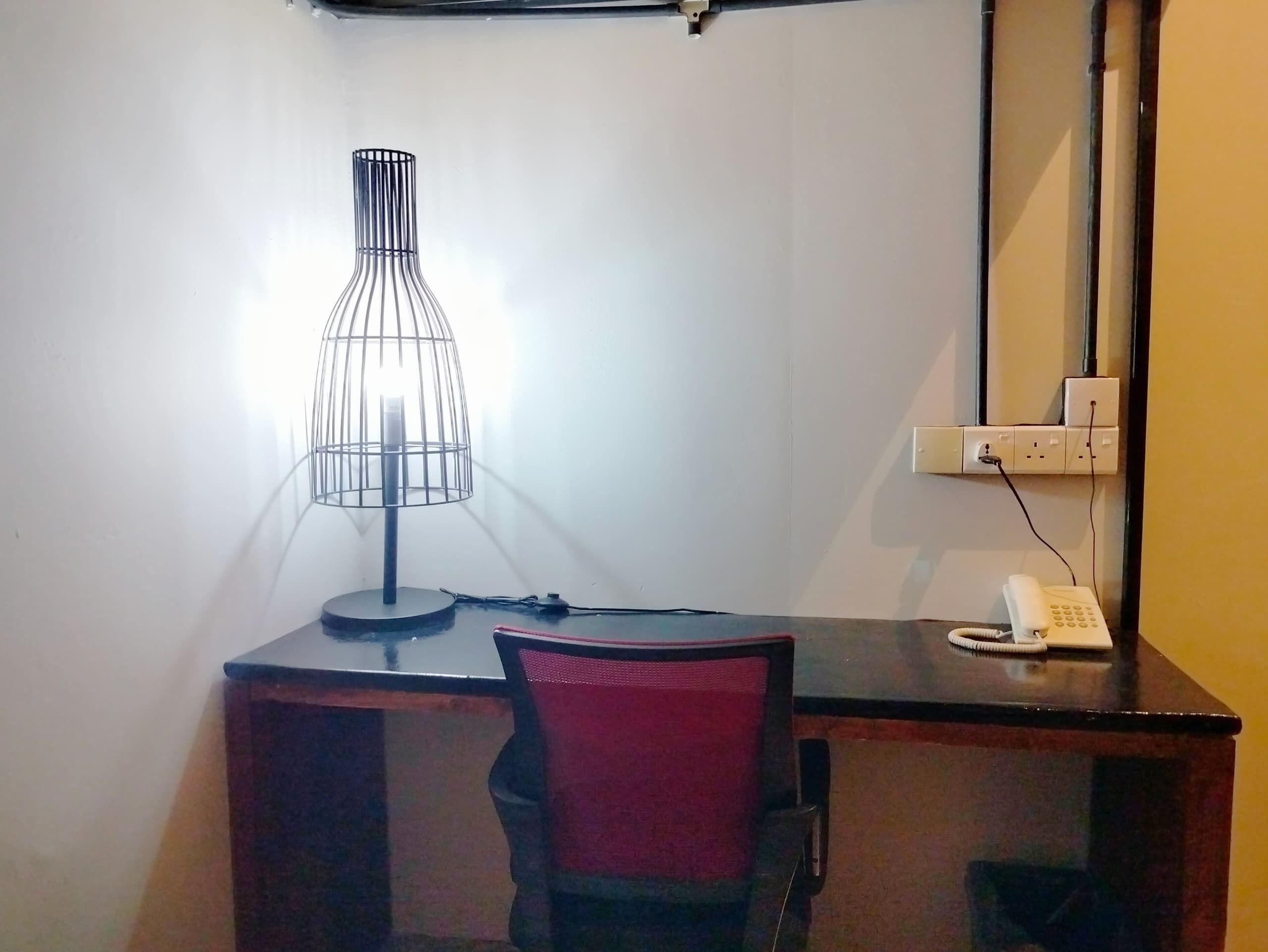 A desk with a lamp, chair, and a phone.