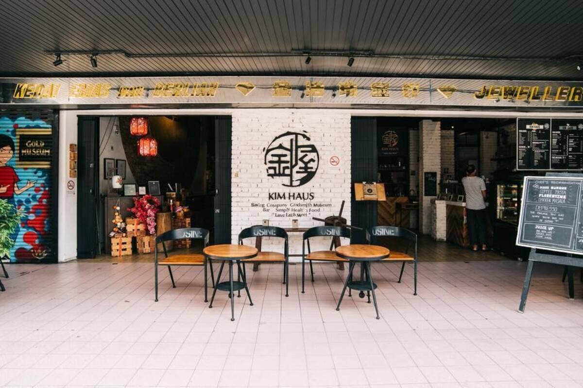 Un espace extérieur aménagé avec des tables et des chaises, situé devant un bâtiment sur lequel on peut lire l’inscription « Kim Haus ».
