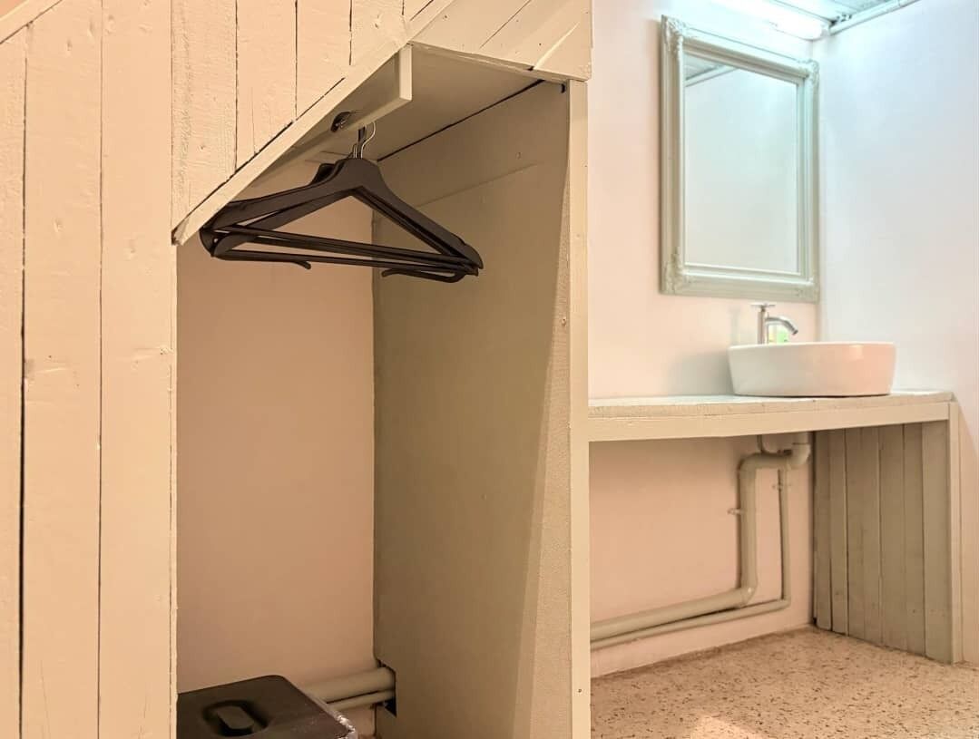 Een badkamer met een witte wastafel, een spiegel en een zwarte hanger.