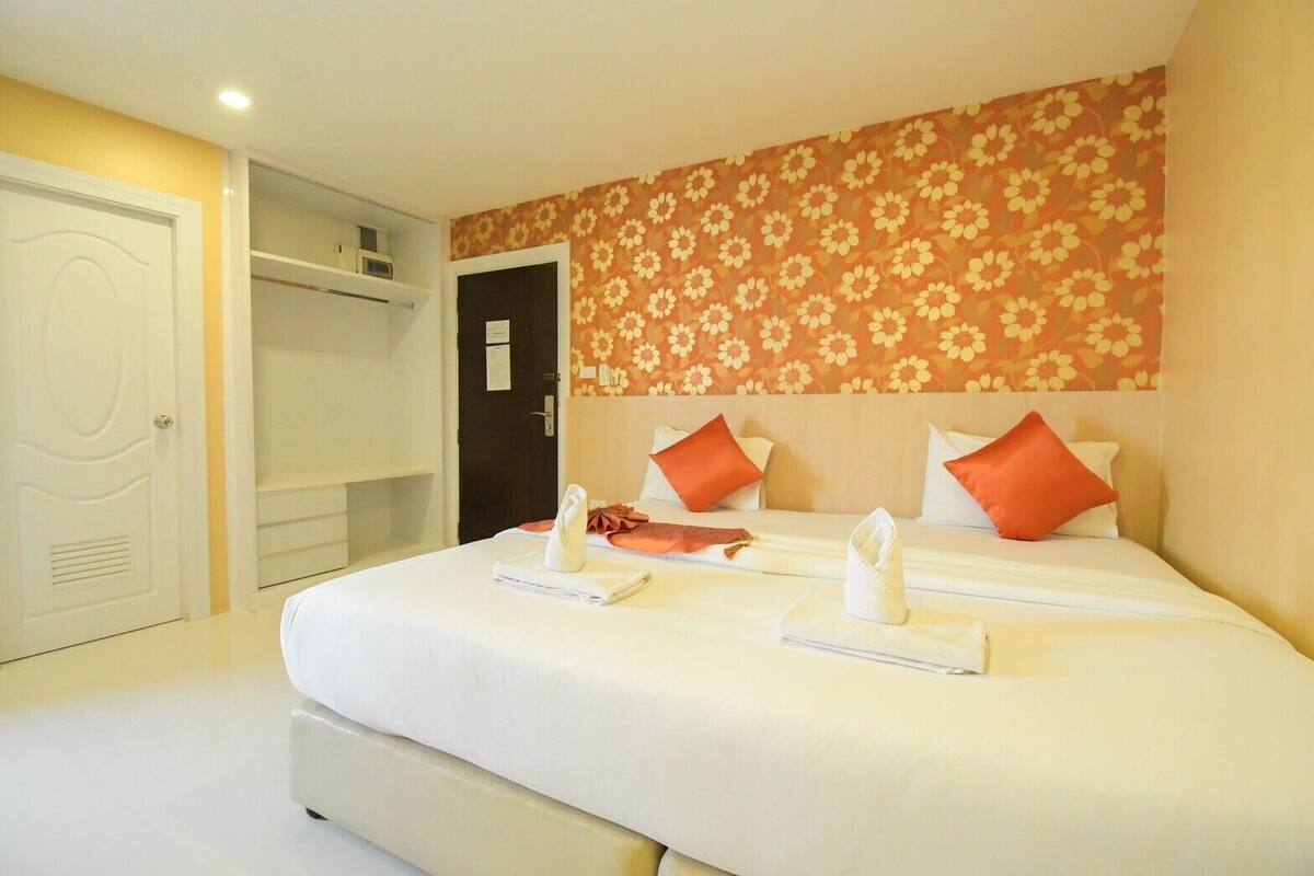 A hotel room with a large bed, two pillows, a nightstand, and a wardrobe.