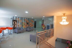 A modern lobby with a staircase, seating area, and decorative wall panels. - Familyhotel (Khon Kaen)