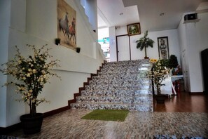 A staircase with a stone pattern, a potted plant, and a painting on the wall. - Pranee Amata (Koh Tao)