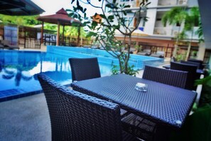 A poolside area with wicker furniture and a glass on the table. - Pranee Amata (Koh Tao)