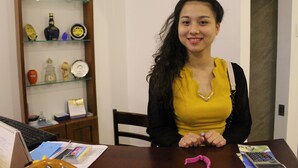 Una persona sentada a una mesa de madera con una computadora portátil, documentos y una calculadora.