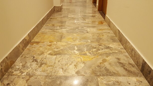 Un pasillo con piso de mármol pulido y paredes blancas.