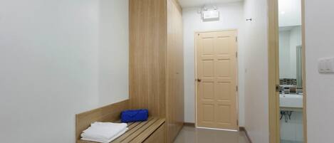 A hallway with a wooden bench, a door, and a bathroom visible through an open door.