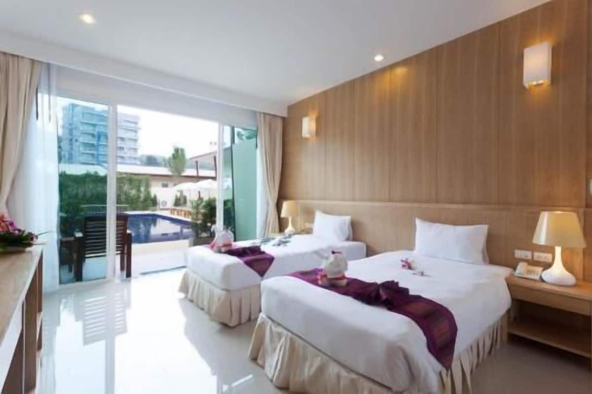 Ein Hotelzimmer mit zwei Betten, einem Balkon und Blick auf einen Pool und Gebäude.