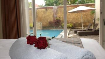 A bed with white towels and two red roses.