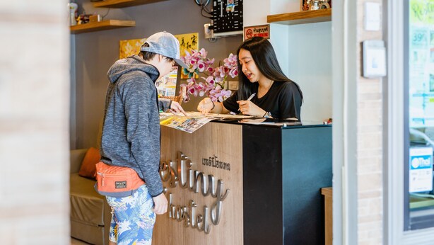A reception desk with a sign that reads "extiny hostel". - Restiny Hostel (Bangkok)